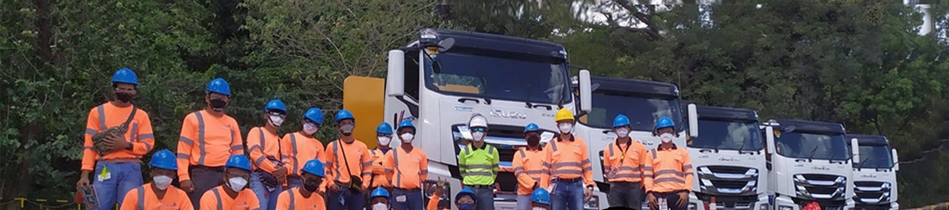 PDSA trainees in safety gear lined up in front of a row of trucks